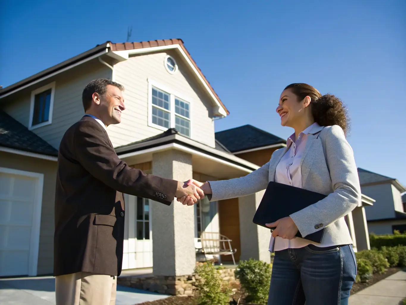 A professional real estate agent shaking hands with a client in front of a modern office building in Dallas, symbolizing trust and partnership.